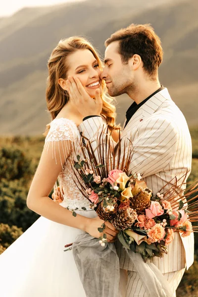 Güzel, mutlu, mutlu, birbirine aşık genç bir çift, dağlarda sarılıyor, arka planda güzel bir düğün çifti. Yüksek kalite fotoğraf