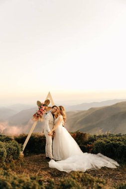 Dağlarda güzel bir düğün töreni, birbirine aşık bir çift, el ele tutuşup gülümsüyor. Yüksek kalite fotoğraf