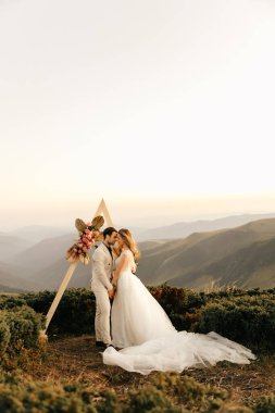 Dağlarda güzel bir düğün töreni, birbirine aşık bir çift, el ele tutuşup gülümsüyor. Yüksek kalite fotoğraf