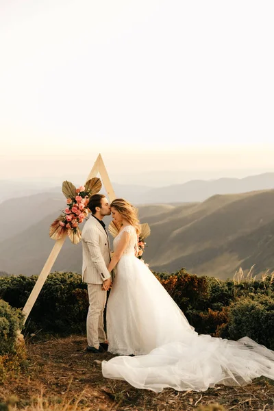 Beautiful wedding ceremony in the mountains, wedding couple in love hold hands and smile. High quality photo