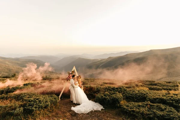 Beautiful wedding ceremony in the mountains, wedding couple of newlyweds in love hug and smile, wedding in nature. High quality photo