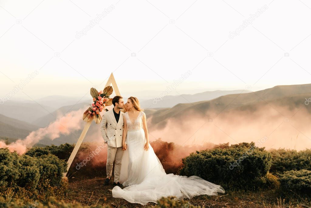 Beautiful wedding ceremony in the mountains, wedding couple of newlyweds in love hug. High quality photo