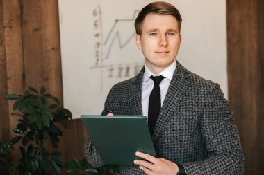 Başarılı genç işadamı ve ofis çalışanı ellerinde belgelerle bir klasör tutuyor ve kağıda notlar yazıyor. Yüksek kalite fotoğraf