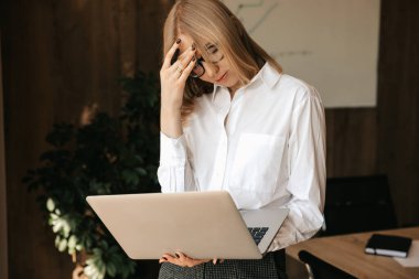 Kadın ofis çalışanı, ofiste internet üzerinde çalışırken dizüstü bilgisayarda zor görevler yapıyor. Stresli bir durum, baş ağrısı. Yüksek kalite fotoğraf