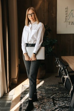 Beyaz gömlekli ve gözlüklü güzel bir iş kızı şirketin gelişiminin grafiği olan bir tahtanın arka planında duruyor. Yüksek kalite fotoğraf