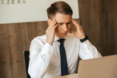 Headache, workload, a hard task, a man who is tired at his workplace. Working at a computer remotely. High quality photo