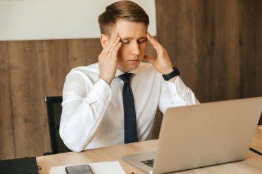 Headache, workload, a hard task, a man who is tired at his workplace. Working at a computer remotely. High quality photo
