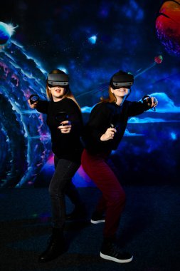 Sanal gözlüklü iki genç kız kardeş birlikte eğleniyor ve video oyunları oynuyorlar.