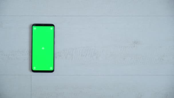 Mart telefon plats på bordet vit med grön skärm, Närbild mobilen är på den bruna skrivbordet med chroma key, Grön skärm telefon, reglaget och ovanifrån. — Stockvideo