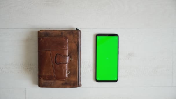 Masanın üzerinde yeşil ekranlı telefon, üstten defter ve çanta görünümü, akıllı telefon kromakey ekran kopyalama alanı — Stok video