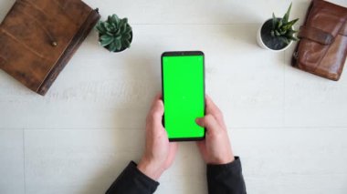 Masanın üzerinde yeşil ekranlı telefon, üstten defter ve çanta görünümü, akıllı telefon kromakey ekran kopyalama alanı 