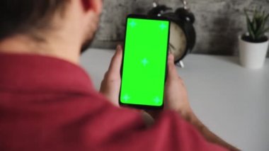 Beyaz masadaki bir adam elinde yeşil ekranlı bir cep telefonuyla oturuyor. Akıllı telefonların kromakey ekranını yakın planda tarayıp dinlediler. Ekleme ve anahtarlama için hazır video