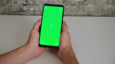 Beyaz masadaki bir adam elinde yeşil ekranlı bir cep telefonuyla oturuyor. Akıllı telefonların kromakey ekranını yakın planda tarayıp dinlediler. Ekleme ve anahtarlama için hazır video
