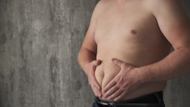 Nahaufnahme dicker Mann berühren den Bauch beim Schütteln der Massage. Er ist sehr dick und hat Probleme mit Bauchschmerzen, weil er zu viel isst. Ein Mann massiert seinen Bauch. Kampf gegen Übergewicht — Stockvideo