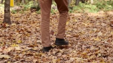 Ayaklarını yere basarak yürüme videosu. Sonbahar sarı yaprakları. Şehir parkında klasik ayakkabılı adamlar