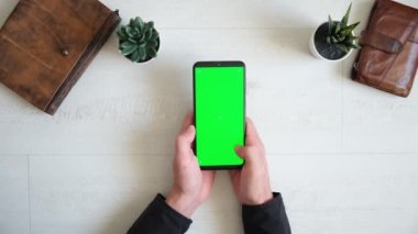 Masanın üzerinde yeşil ekranlı telefon, üstten defter ve çanta görünümü, akıllı telefon kromakey ekran kopyalama alanı 
