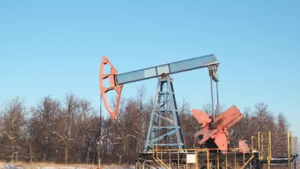 Oil pump drilling rig or rocking machine against the blue winter sky. Cold, harsh winter and lots of snow . Oil industry in Russia and Norway. crude oil prices concept.time-lapse accelerated video — Stock Video