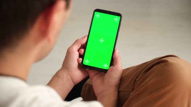 Macchina fotografica portatile: Punto di vista della donna al telefono con schermo verde per spazio copia. Chromakey 20s Lady Guardando le notizie video sul divano da vicino. Toccare per fare clic sul centro dello schermo Filmato Stock