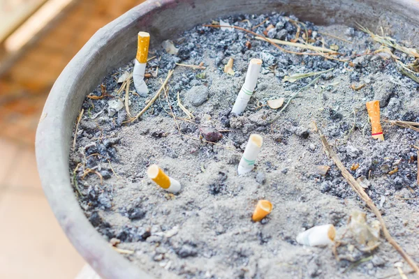 Копченые сигареты Задницы в общественной пепельнице, избирательный фокус — стоковое фото