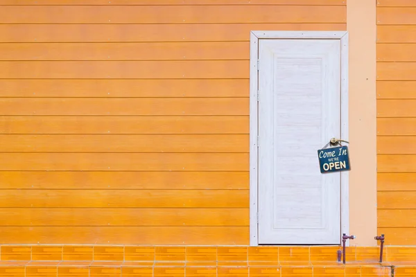 Puerta de madera blanca y la pared naranja con vieja placa de metal oxidada — Foto de Stock