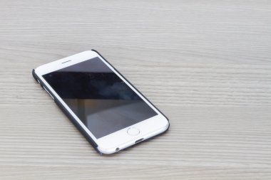 Boş ekran gri ahşap masanın üzerinde yatan ile akıllı telefon