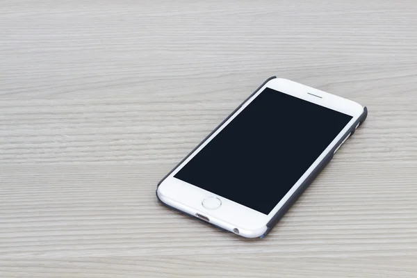 Smart phone con schermo bianco sdraiato sul tavolo in legno grigio — Foto Stock