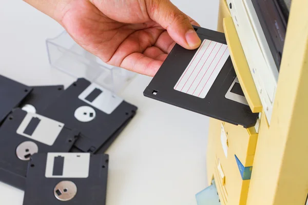 Mano insertando un disquete de 3,5 pulgadas en una ranura para disquete en una computadora de escritorio. Enfoque selectivo . — Foto de Stock