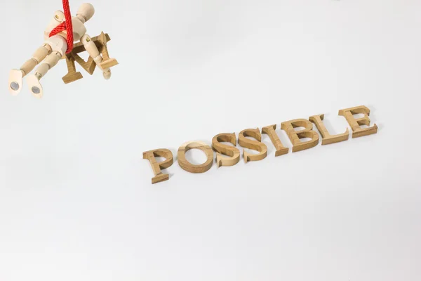 Changing the word impossible to possible with wooden dummy hanging on the red rope — Stock Photo, Image