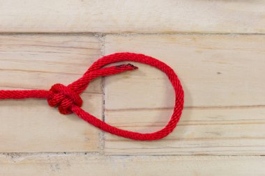 ahşap arka plan üzerinde sıkma kırmızı sentetik halat yapılan Borça düğümü.