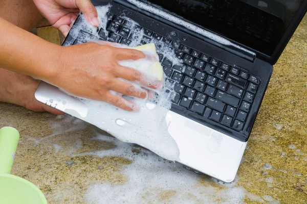 Closeup cleaning computer notebook with dish washing soap, technology concept — Stock Photo, Image