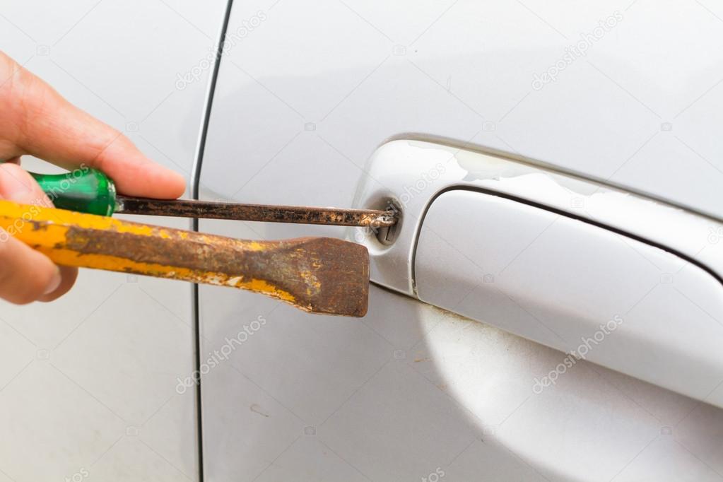 horizontal photo of closeup locksmith will open bronze car door white screwdriver - selective to focus on key hold.