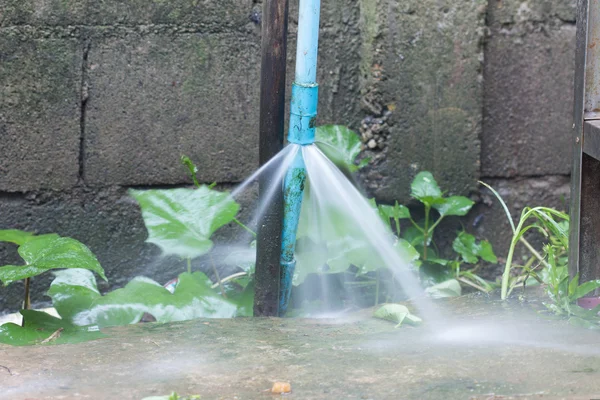 Gamla rostiga pvc-rör med läcka och vatten sprutar ut — Stockfoto
