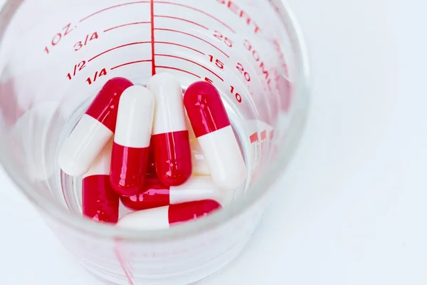 Capsules rouges blanches dans une tasse de verre — Photo