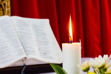 bible open on a table with candle clipart
