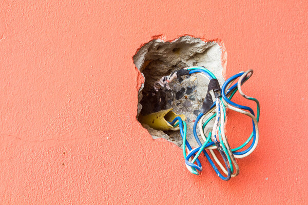 crack hole wall with electric colored wires, copyspace on the le