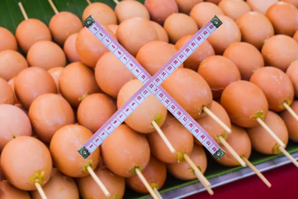 Cross measuring tape on blurred grilled eggs with bamboo skewers — Stock Photo, Image