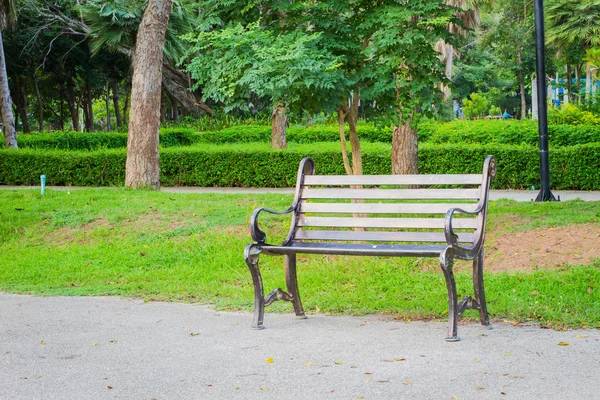 Gartenstuhl aus Metall auf Betonboden mit grünem Gras dahinter. — Stockfoto