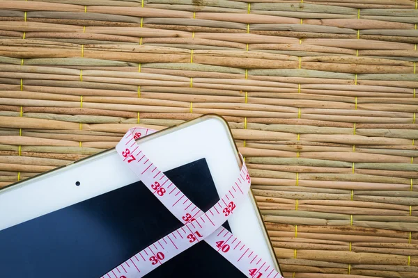 Tablet computer on traditional mat with  measuring tape for weig — Stock Photo, Image