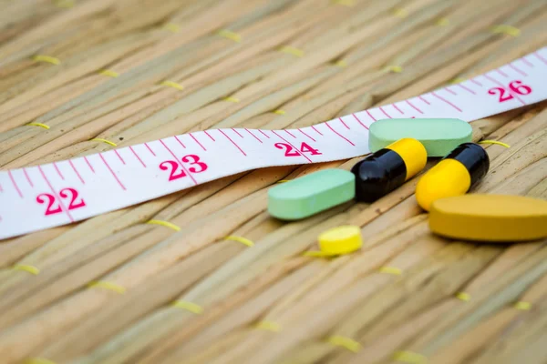 Таблетки и измерительная лента на традиционном коврике. диета или похудеть — стоковое фото