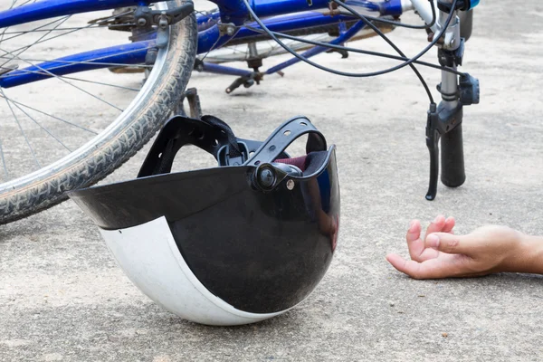 Kolo a helma, ležící na silnici s rukou člověka, accid — Stock fotografie