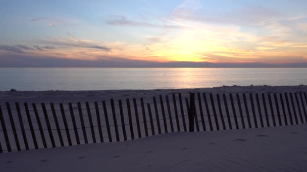 Сніговий паркан на пляжі з травою на заході сонця — стокове відео