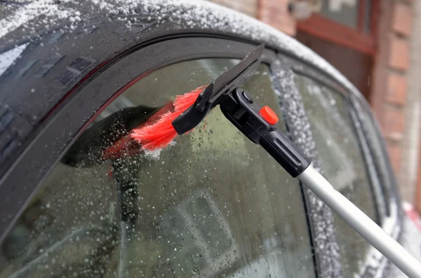 Clearing of a sleet at a car window with use of a brush — Stock Photo, Image