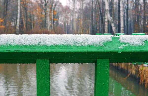 Snow and rain on green wooden railing. Fragment. — Stock Photo, Image