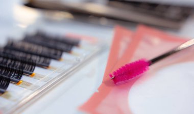 Beyaz masada takma kirpik ve kırmızı kirpik fırçası.