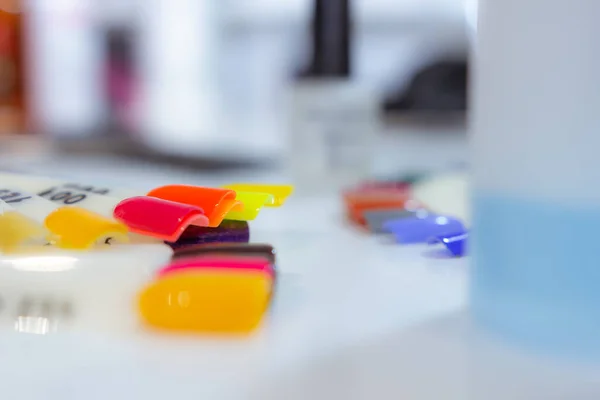 Beyaz güzellik odasındaki beyaz masada çok renkli oje örnekleri.