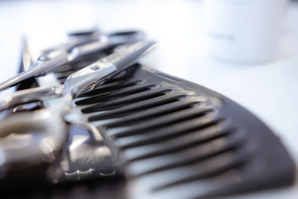 Makas ve makyaj tarağı beyaz masada.