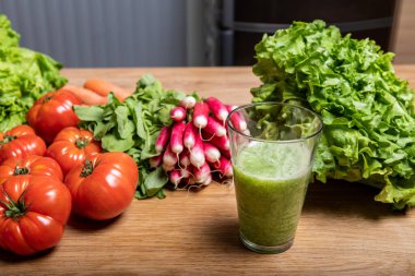 Sebze suyu ve çeşitli organik sebze hasadı ahşap mutfak masasında.