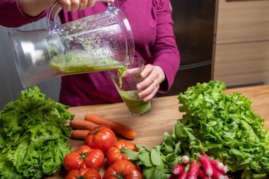 Vejetaryen kadın detoks için sebze suyu yapıyor.