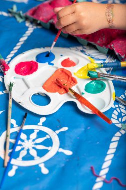 Çocuk fırçayla yumurta kutusu boyuyor.