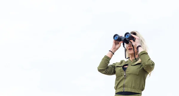 Frau Blickt Durch Fernglas Steht Der Natur Vor Einem Hintergrund — Stockfoto
